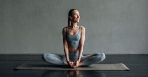 Жена седи в поза за йога на постелка