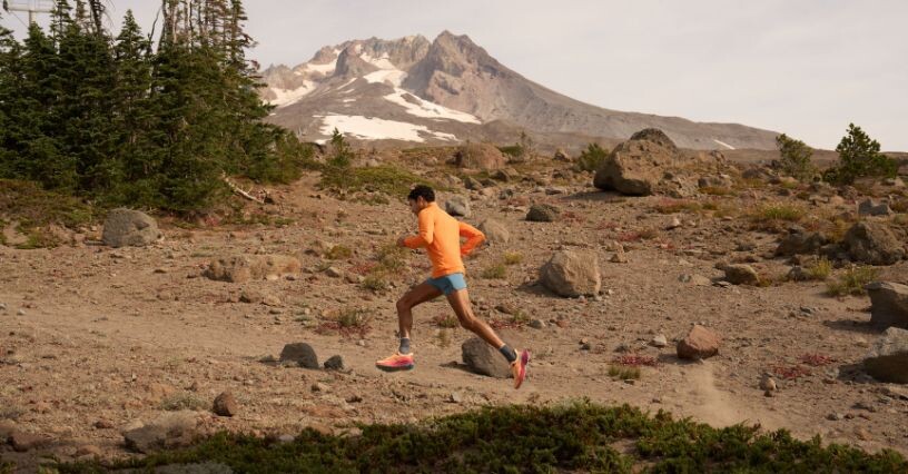Човек тича по планинска пътека с фон на планини