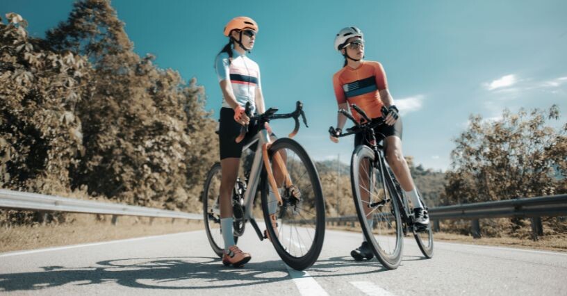 Двама велосипедисти стоят на път с велосипеди