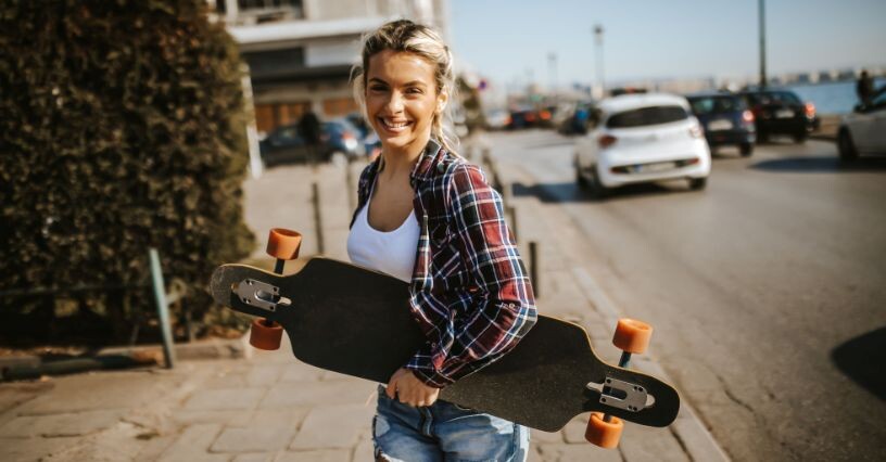 Човек носи лонгборд по улица