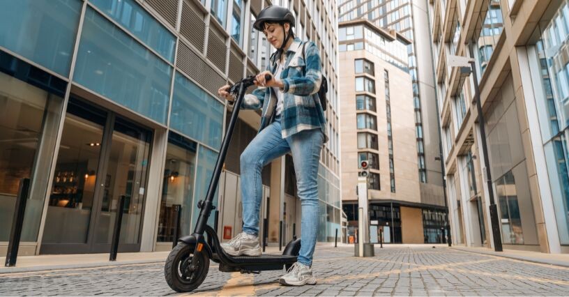 Човек кара електрическа тротинетка по улиците на града