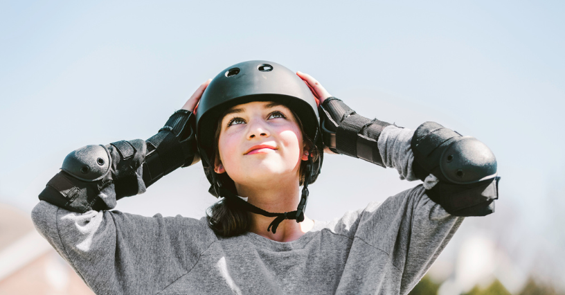 Момиче носи каска и протектори за ролери