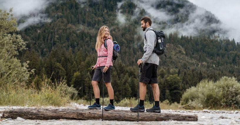 Двама души се разхождат с туристическо оборудване в планината