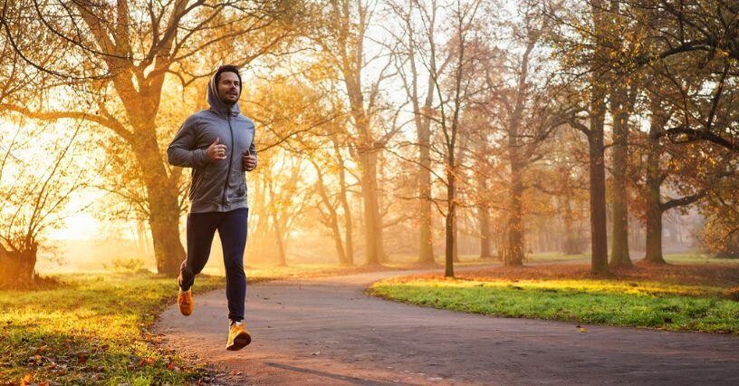 Човек тича в парк през есента сутринта